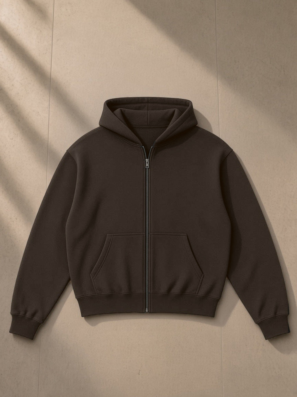 Unisex fleece zip-up boxy hoodie in Brown, laid flat on pale limestone, front view