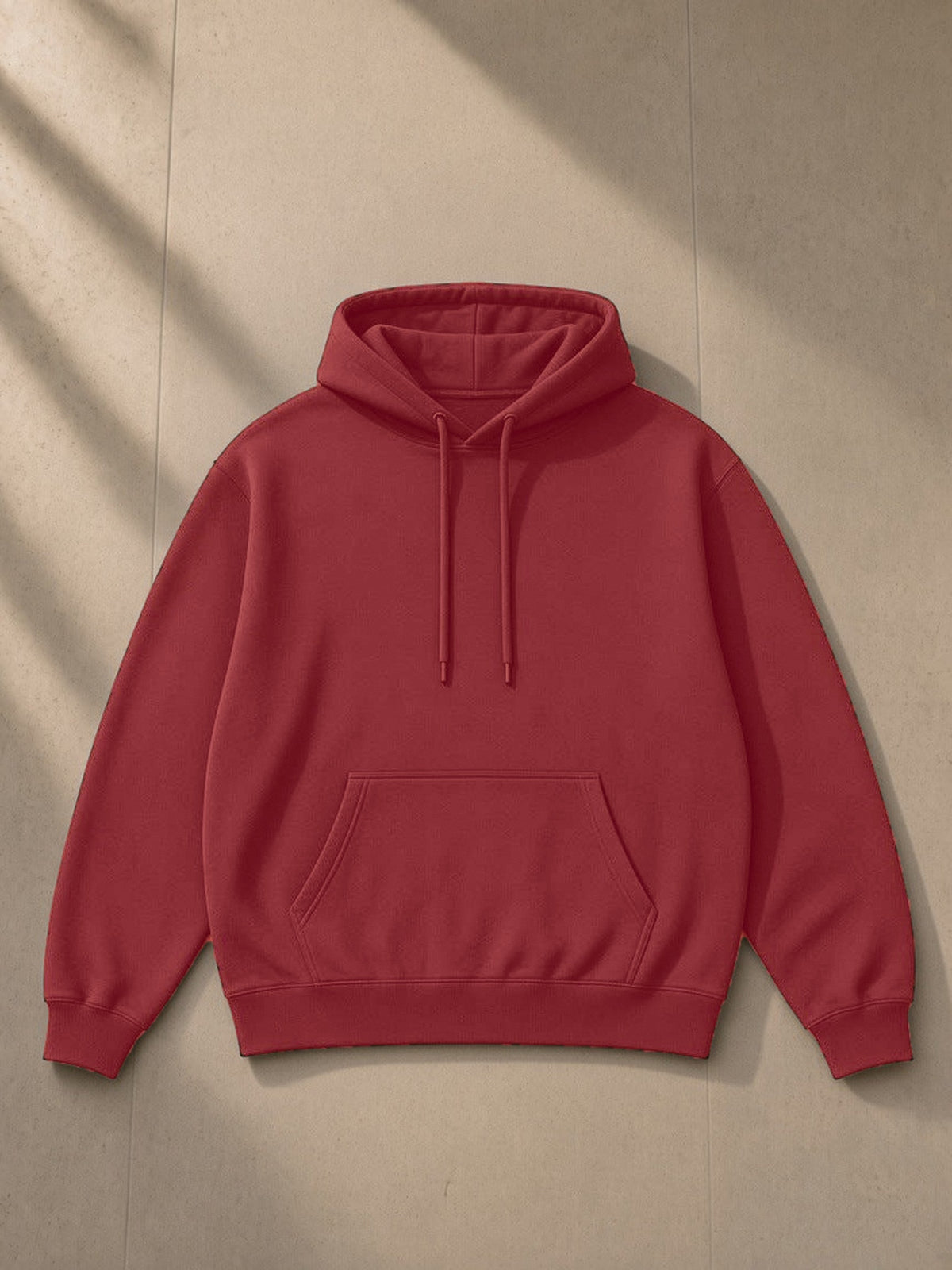 Unisex oversized drop shoulder hoodie in Red, laid flat on pale limestone, front view