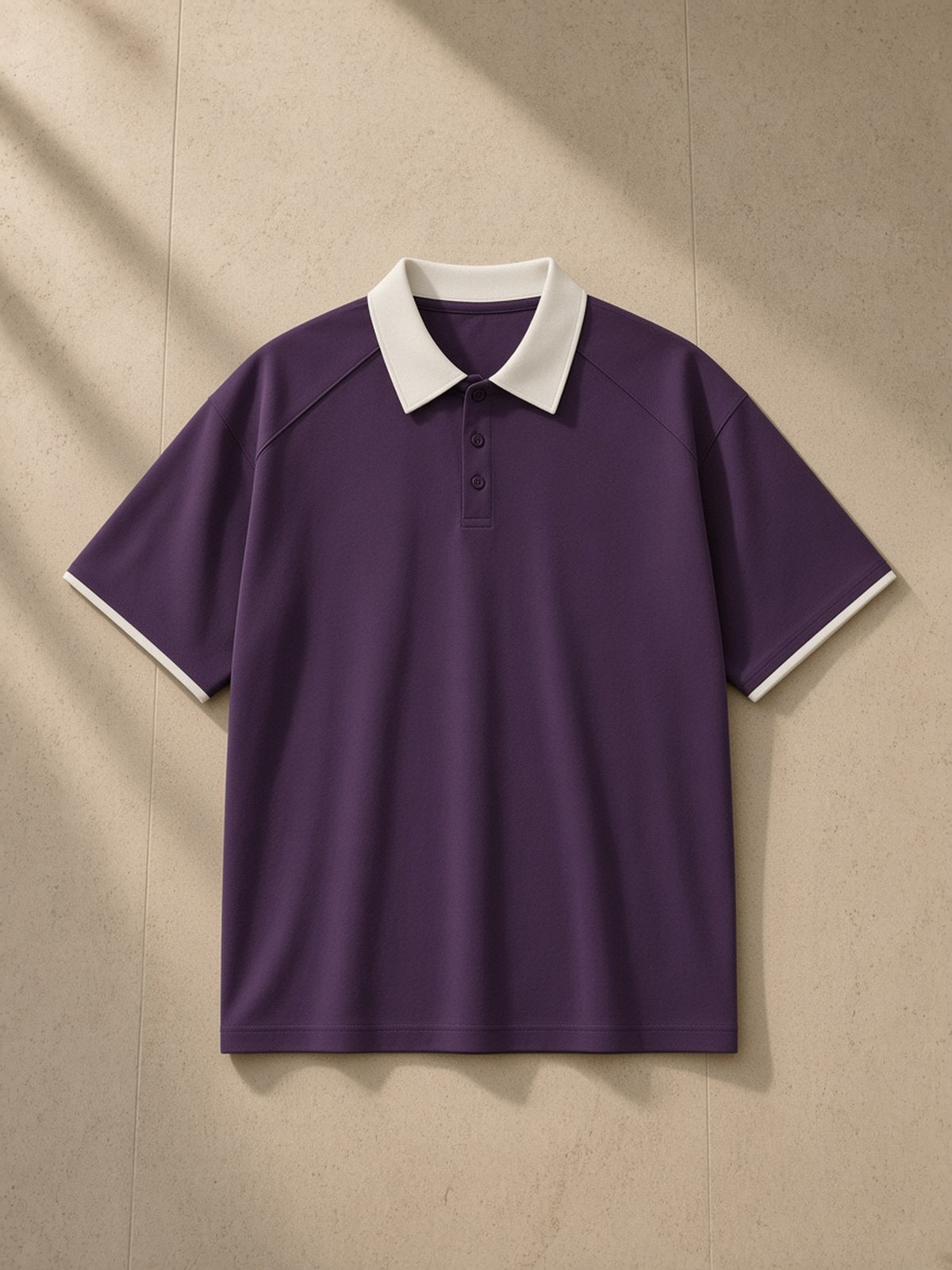 Contrast Collar Raglan Polo Shirt in Purple, laid flat on pale limestone