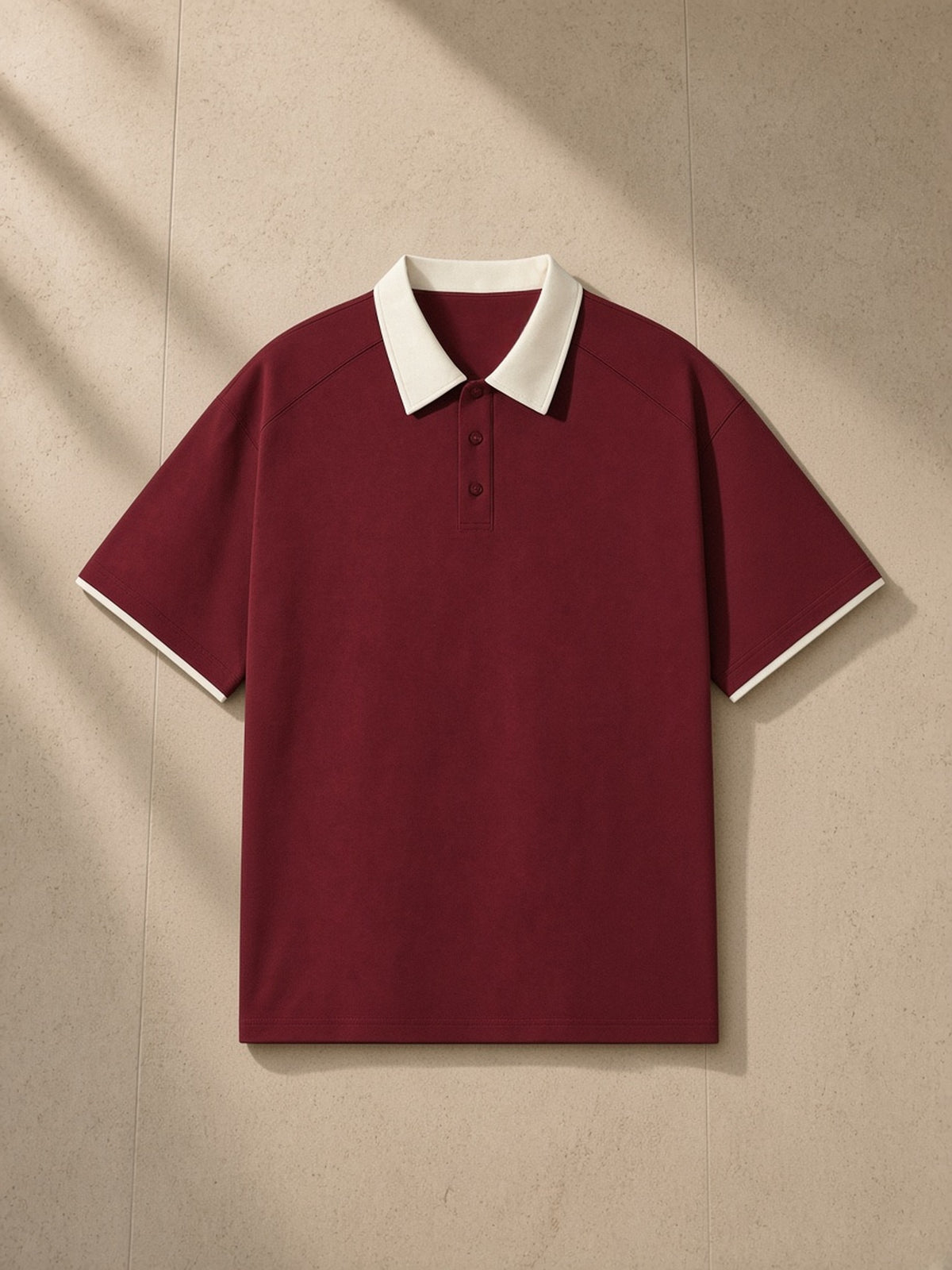 Contrast Collar Raglan Polo Shirt in Wine Red, laid flat on pale limestone