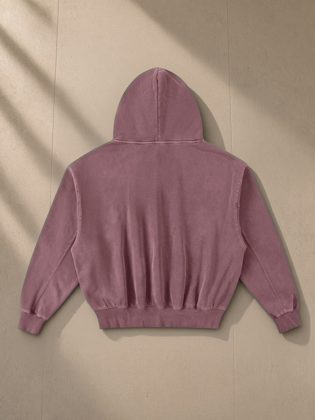 Frayed Enzyme Washed Fleece Hoodie in Red, laid flat on pale limestone, back view