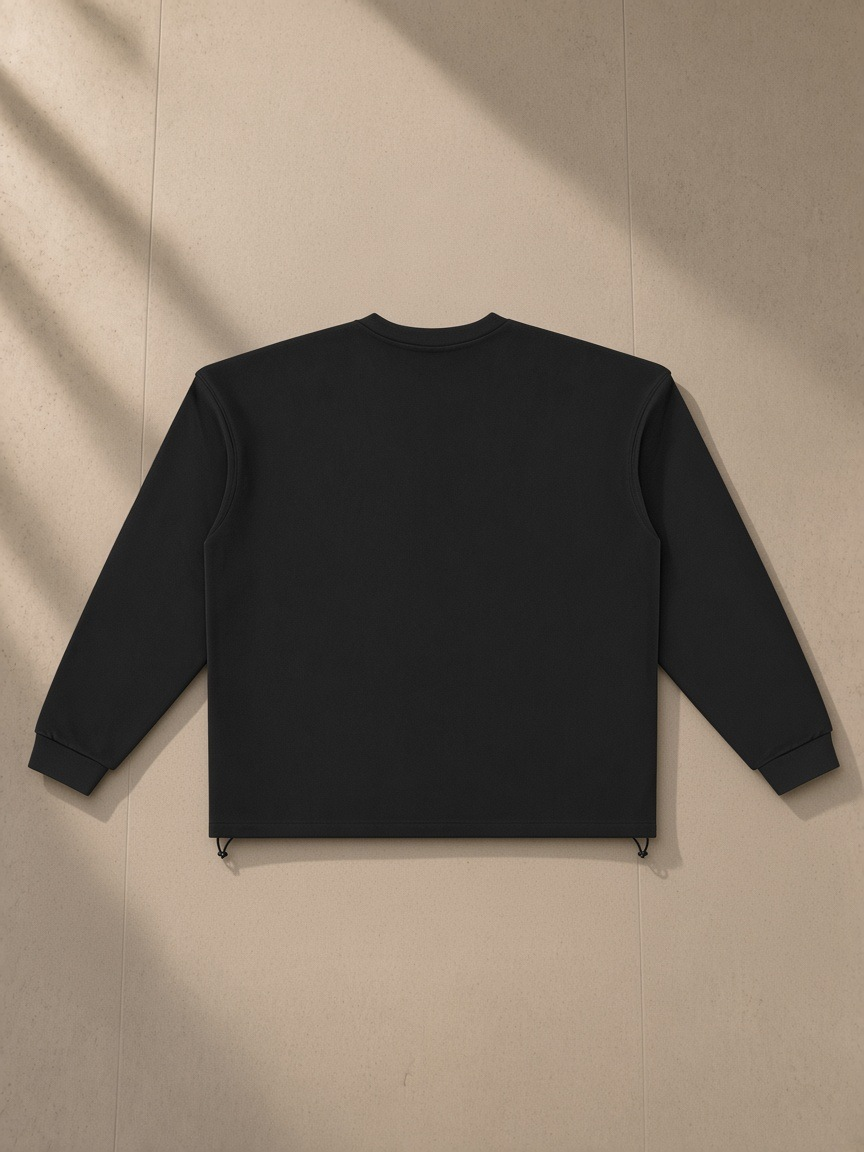 Heavyweight oversized boxy sweatshirt in Black, laid flat on pale limestone, back view