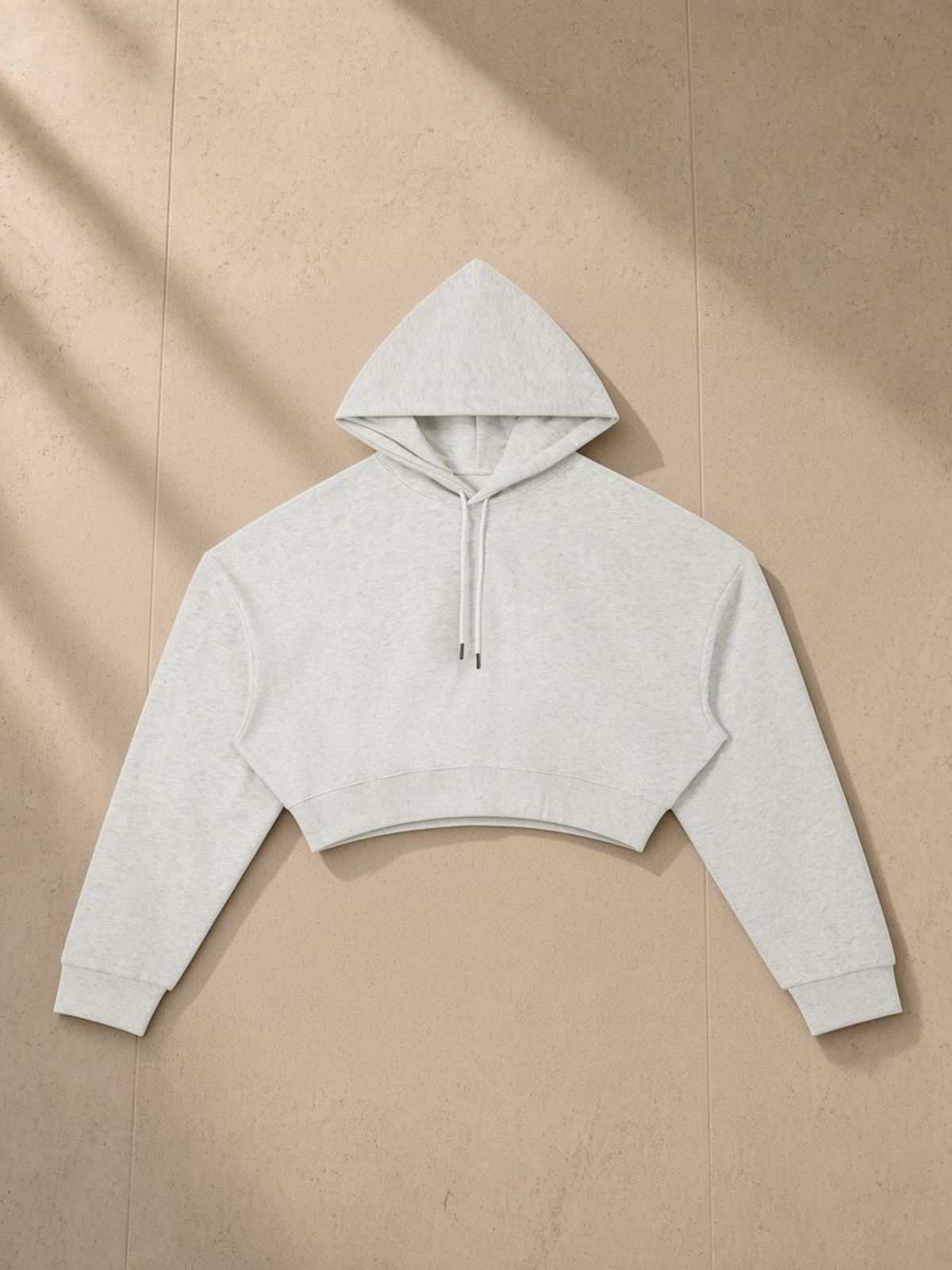 Essential Cropped Hoodie in Oat Gray, laid flat on pale limestone