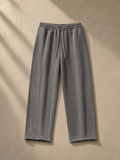Frayed enzyme washed fleece sweatpants in Light Gray, laid flat on pale limestone