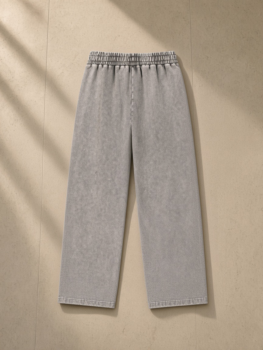 Unisex snow wash heavyweight sweatpants in Light Gray, laid flat on pale limestone, back view