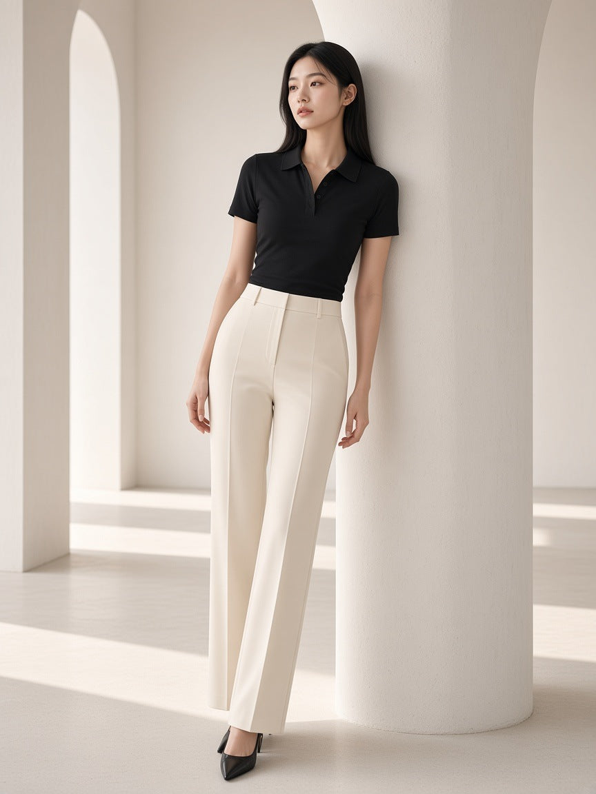 Marcel Afters Bodycon Short Sleeve Polo Shirt in Black, worn by a woman, standing against a white arch in a black polo and cream trousers