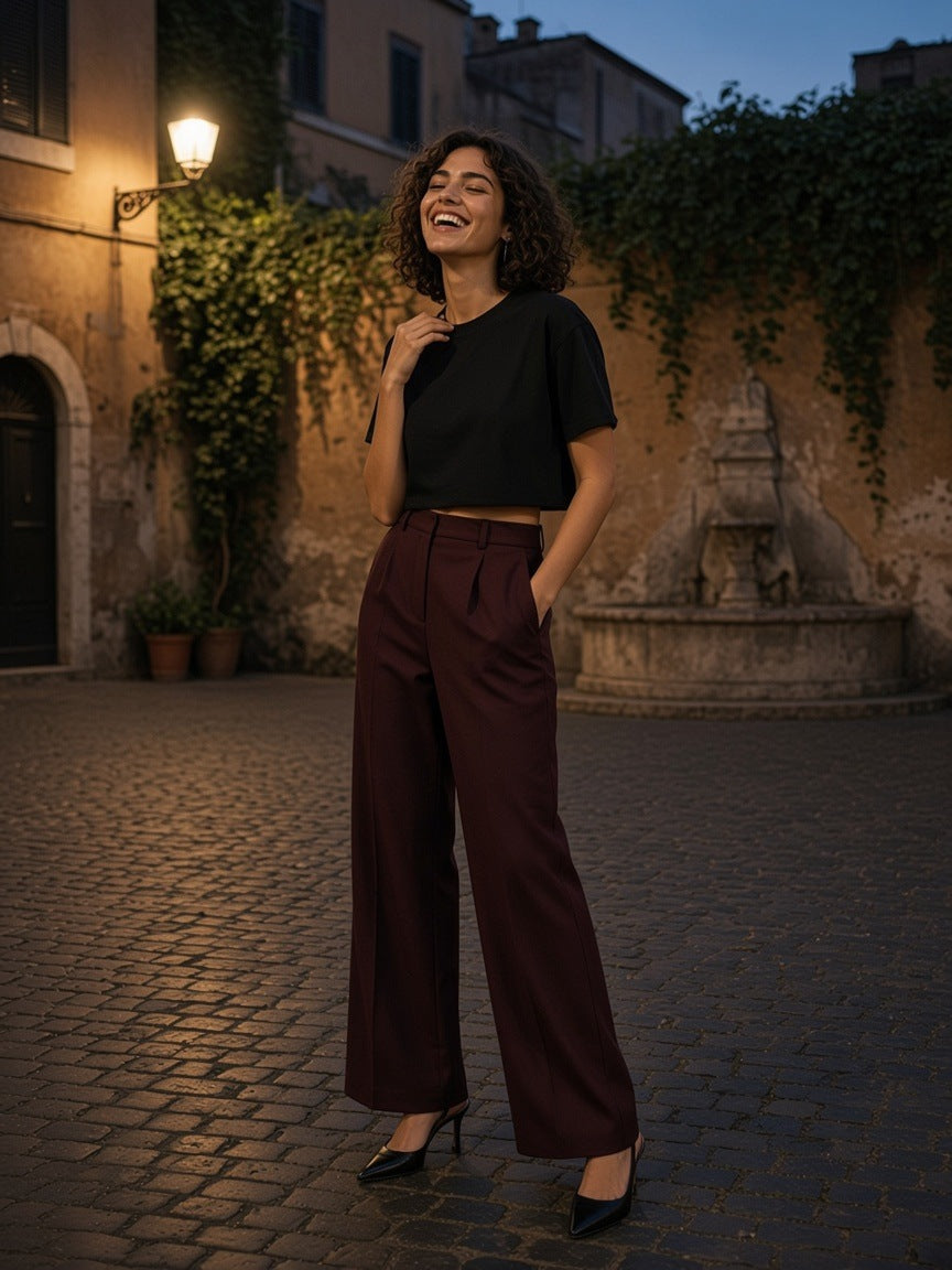 Woman in the Boxy Drop Shoulder Crop T-Shirt in Black and high-rise wide trousers in a Trastevere piazza in Rome at blue hour