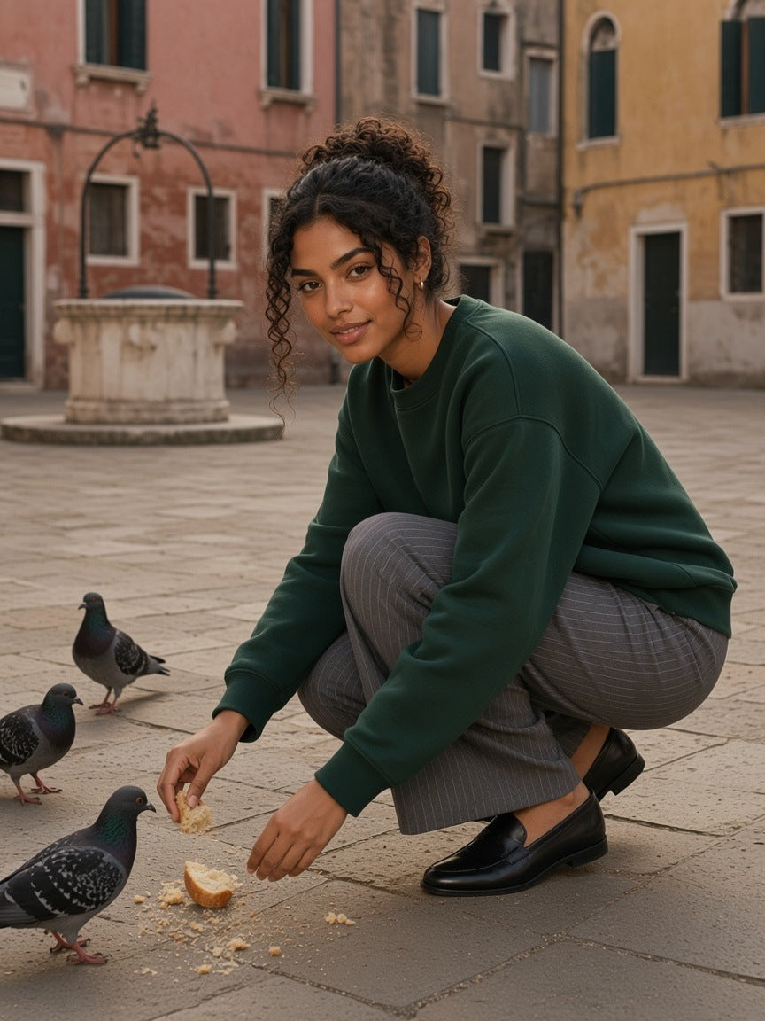 Woman in the Marcel Afters Boxy Fleece Crewneck Sweatshirt in Dark Green against a pink and ochre wall in Mexico City