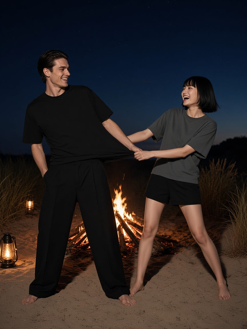 Two people in the Marcel Afters Boxy Mesh Crewneck T-Shirt in Black and Dark Gray by a bonfire in the Sylt dunes