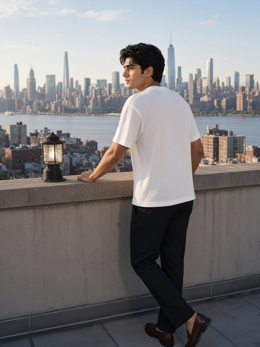 Man in the Boxy Mesh Crewneck T-Shirt in White leaning on a rooftop over the Hudson in New York in the morning