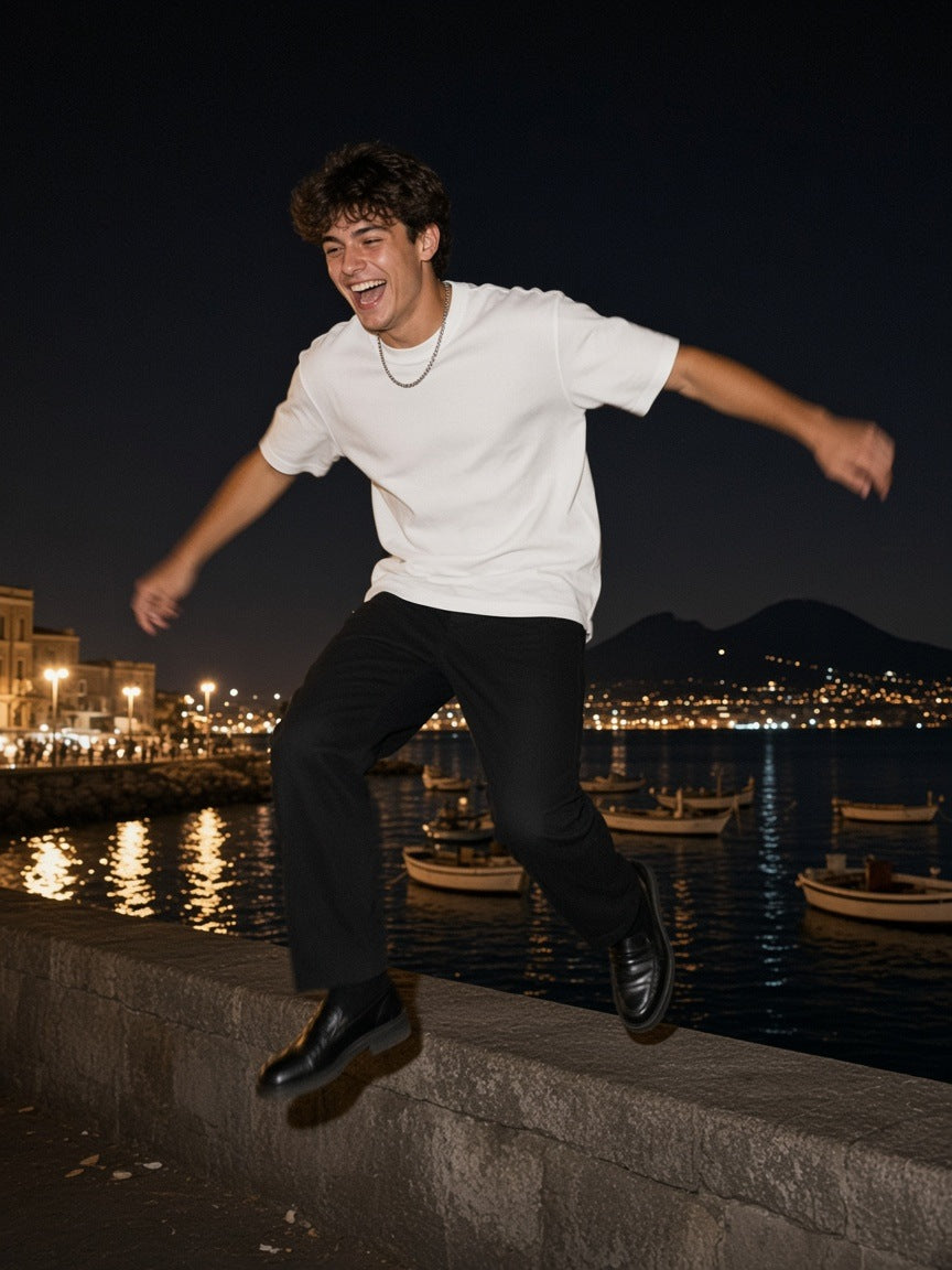 Man in the Boxy Mesh Crewneck T-Shirt in White, leaping off a wall on the Naples waterfront at 2am