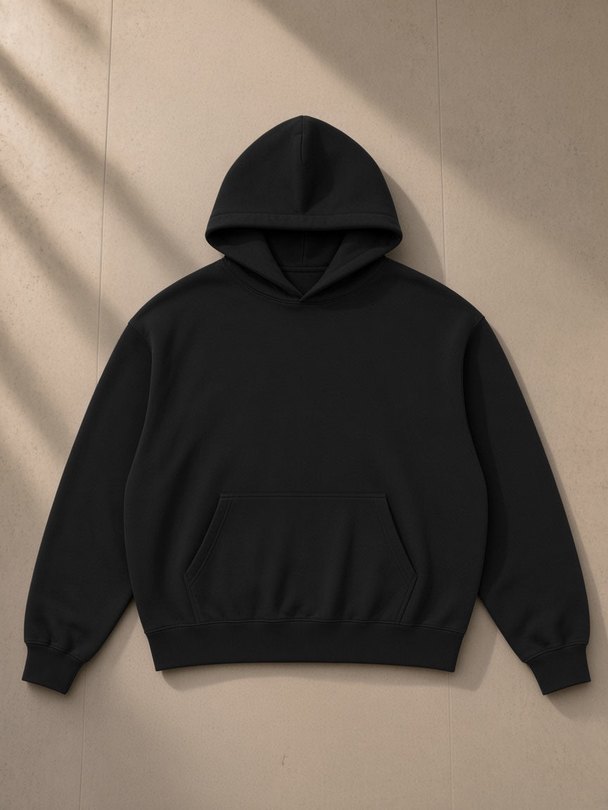 Boxy Oversized Hoodie in Black, laid flat on pale limestone, front view