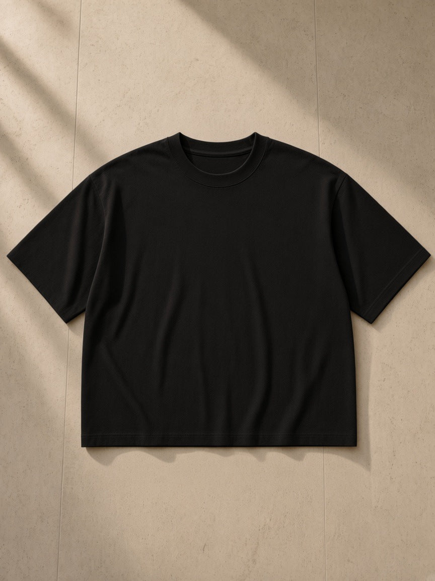 Boxy Oversized T-Shirt in Black, laid flat on pale limestone