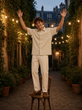 Man in the Boxy Patch Pocket Short Sleeve Shirt in Khaki hanging festoon lights in a Marais courtyard in Paris at dusk