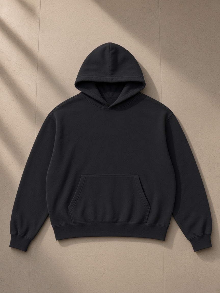 Boxy vintage washed hoodie in Black, laid flat on pale limestone, front view