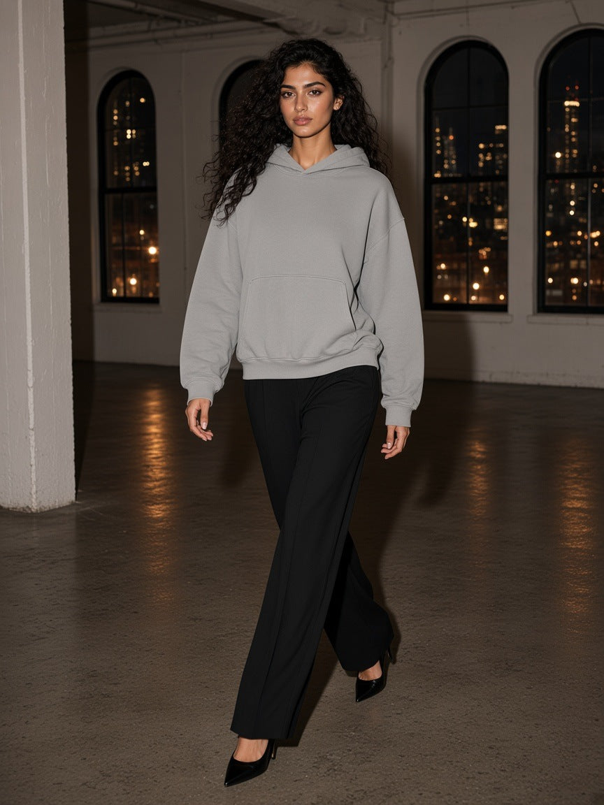 Woman in the Boxy Vintage Washed Hoodie in Light Gray walking through a cast-iron loft in Tribeca, New York at night