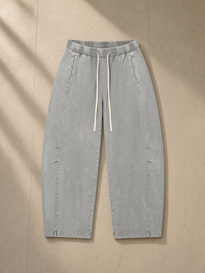 Unisex mineral wash barrel leg pants in Gray, laid flat on pale limestone