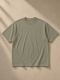 Unisex heavyweight oversized t-shirt in Gray Green, laid flat on pale limestone