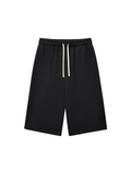 Unisex relaxed drawstring three-quarter sweatpants in Black, front view on white. Marcel Afters