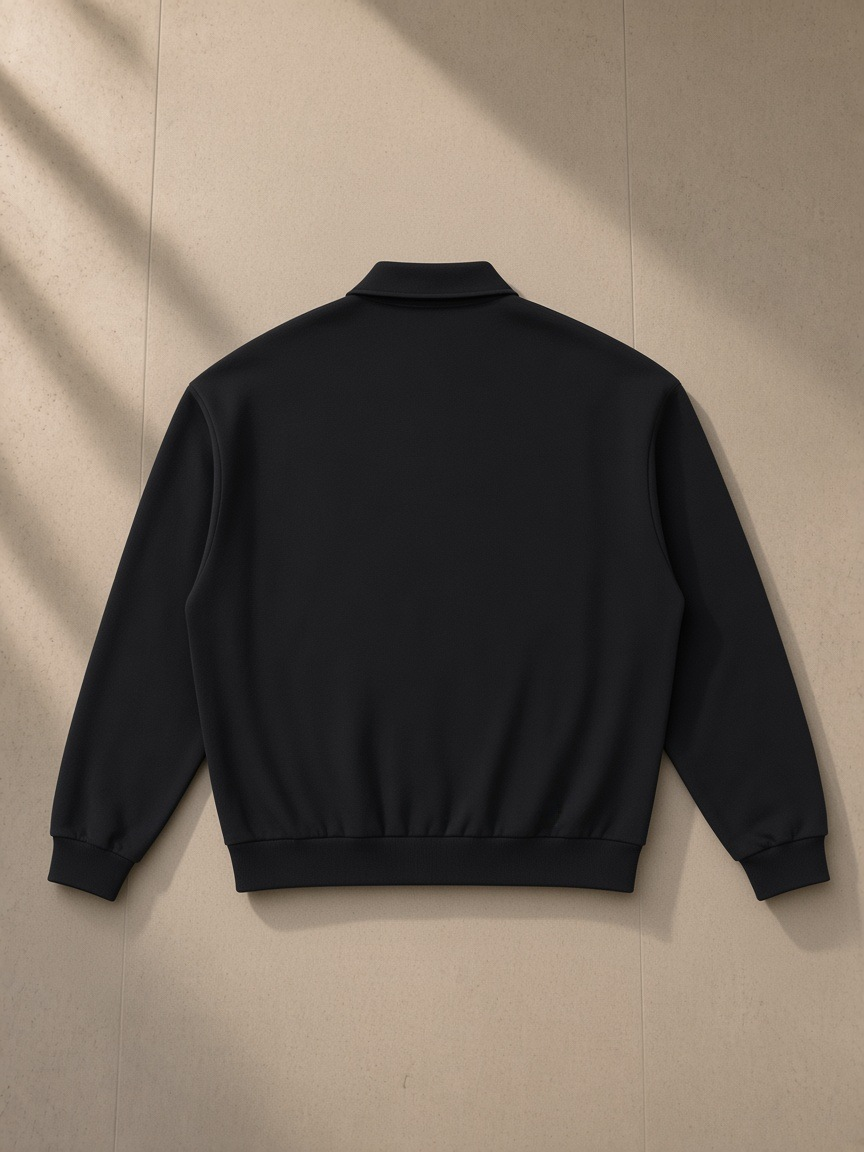 Heavyweight fleece polo sweatshirt in Black, laid flat on pale limestone, back view