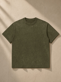 Unisex Mineral Wash Oversized T-Shirt in Olive Green, laid flat on pale limestone