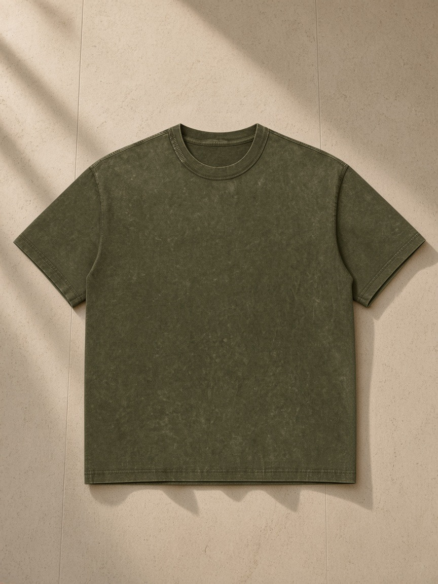 Unisex Mineral Wash Oversized T-Shirt in Olive Green, laid flat on pale limestone