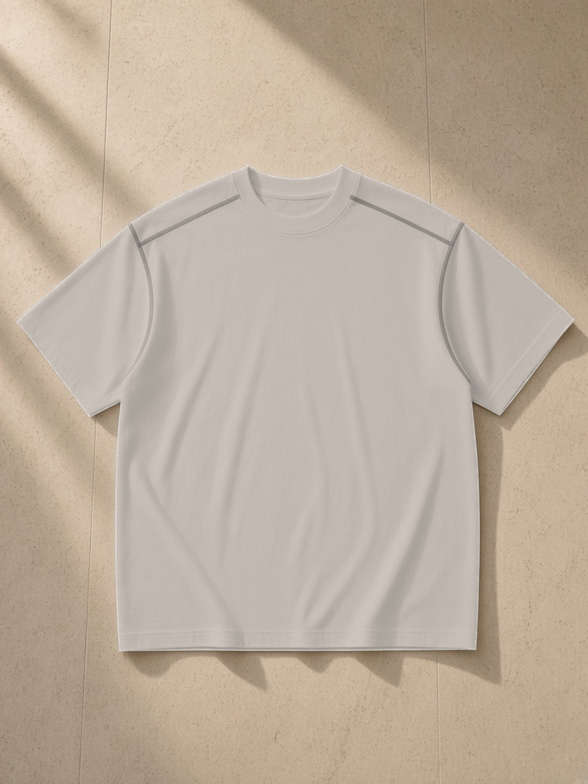 Oversized Contrast-Stitched Cotton Tee in Beige Camel, laid flat on pale limestone, front.