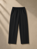 Tapered straight hem sweatpants in Black over a leather lounge chair in a Hong Kong penthouse at night