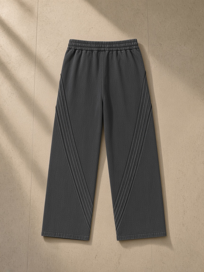 Snow Washed Tape Raw Edge Sweatpants in Black, laid flat on pale limestone, back view