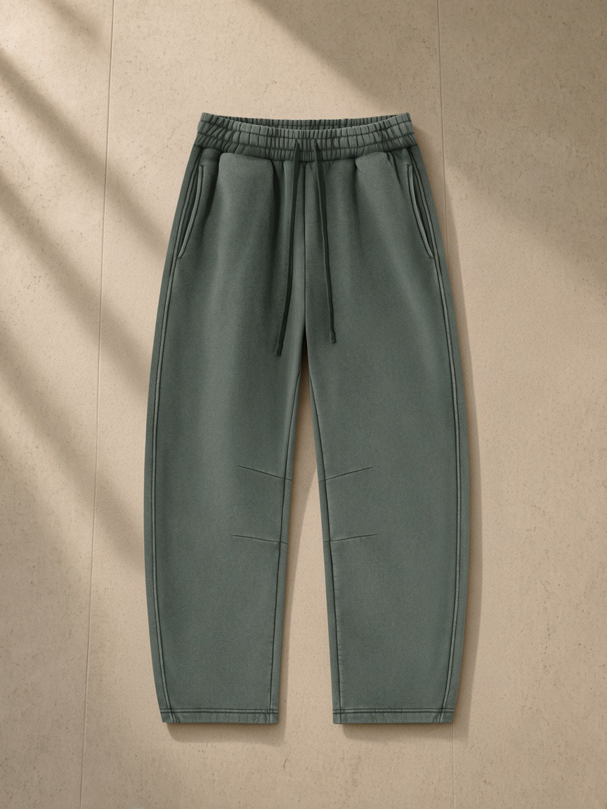 Vintage wash barrel leg fleece sweatpants in Washed Green, laid flat on pale limestone