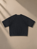 Unisex vintage wash boxy short sleeve sweatshirt in Black, laid flat on pale limestone, back view