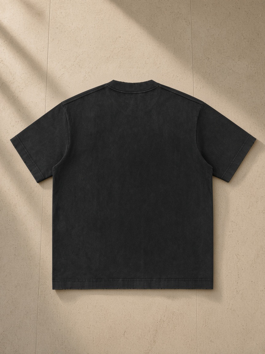 Men's Heavyweight Vintage Washed Frayed T-Shirt in Black, laid flat on pale limestone, back.