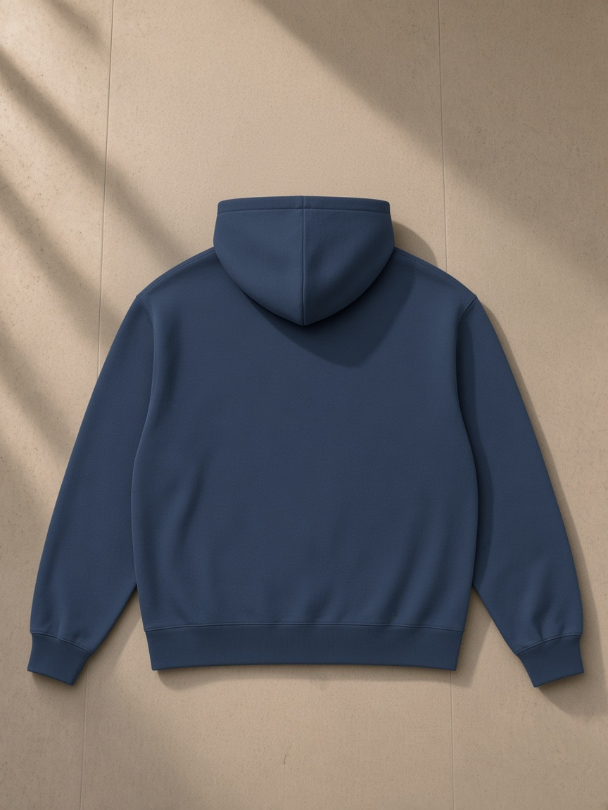 Heavyweight pullover hoodie in Navy Blue, laid flat on pale limestone, back view