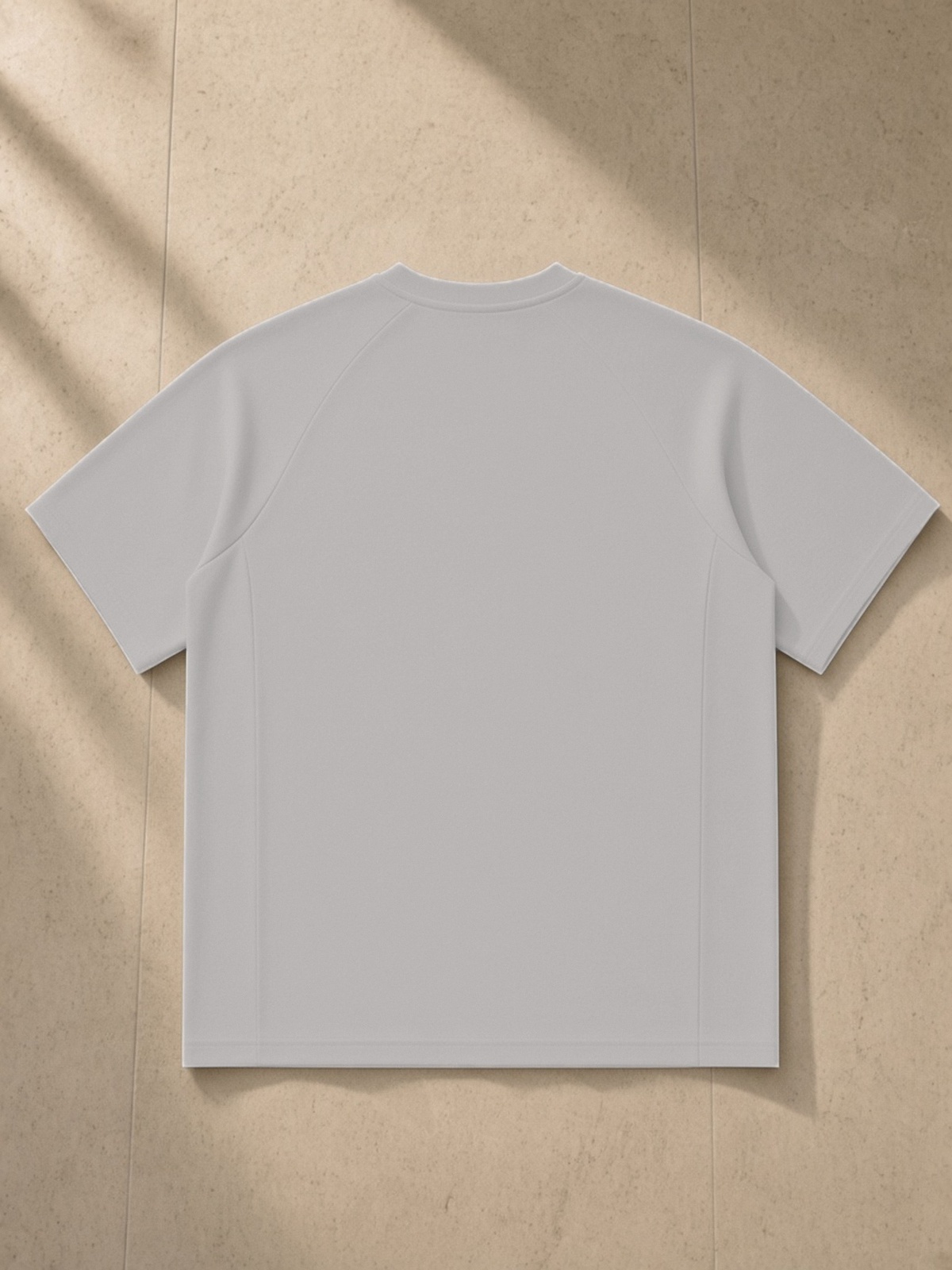 Oversized Paneled Raglan T-Shirt in Light Gray, laid flat on pale limestone, back.