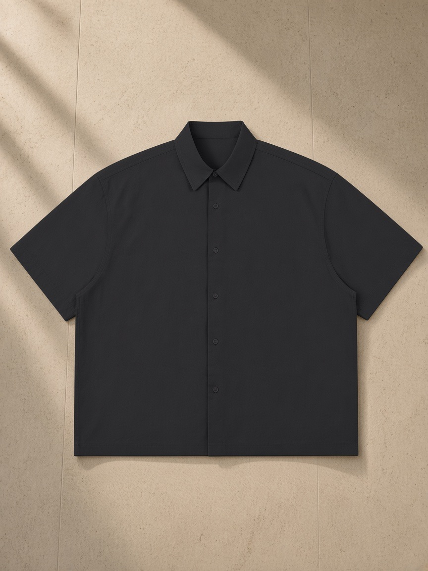 Lightweight Cotton Short Sleeve Shirt in Black, laid flat on pale limestone