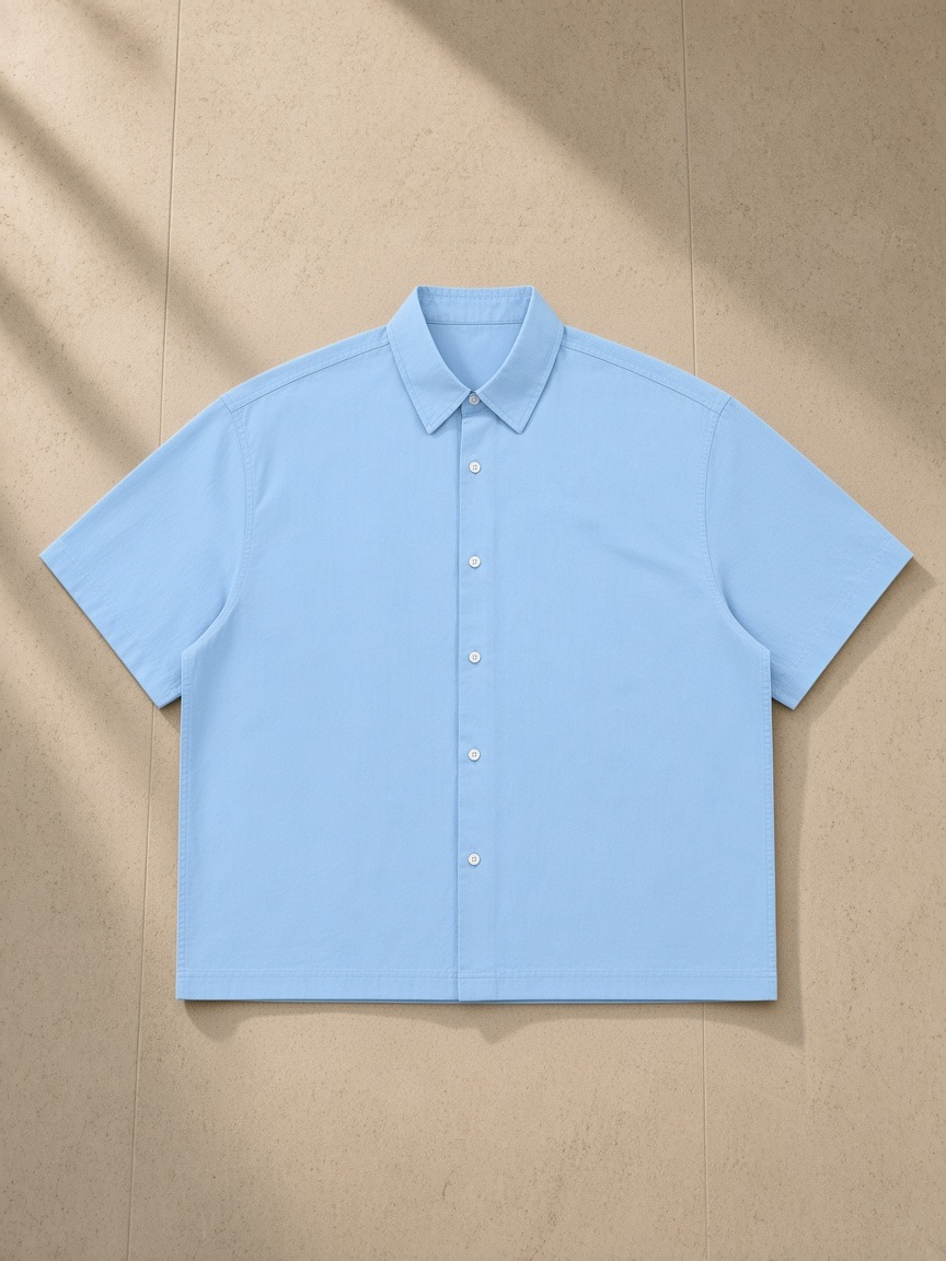 Boxy Short Sleeve Shirt in Blue, laid flat on pale limestone