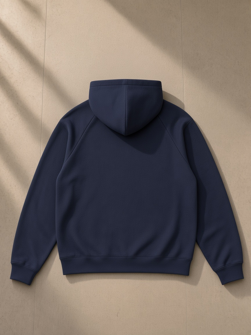 Unisex heavyweight raglan sleeve zip hoodie in Navy Blue, laid flat on pale limestone, back view