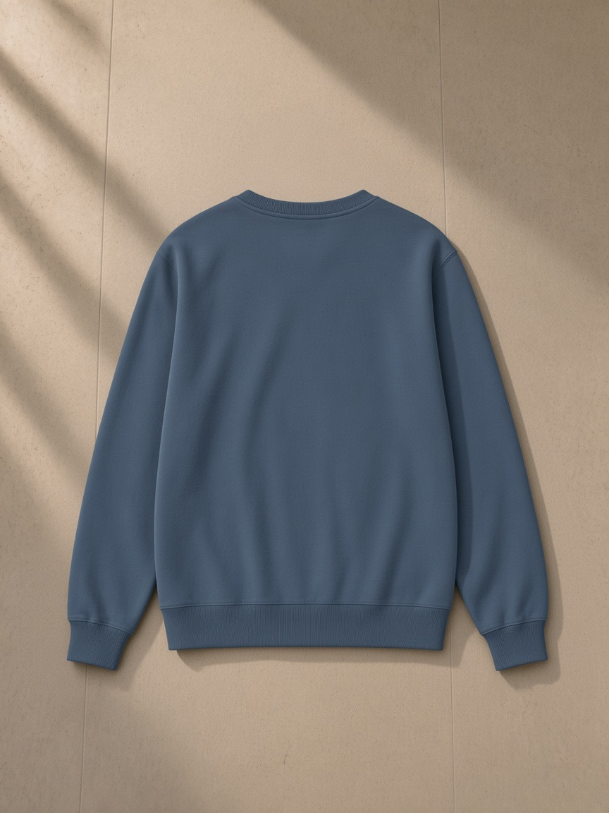 Classic Cotton Sweatshirt in Ink Blue, laid flat on pale limestone, back view