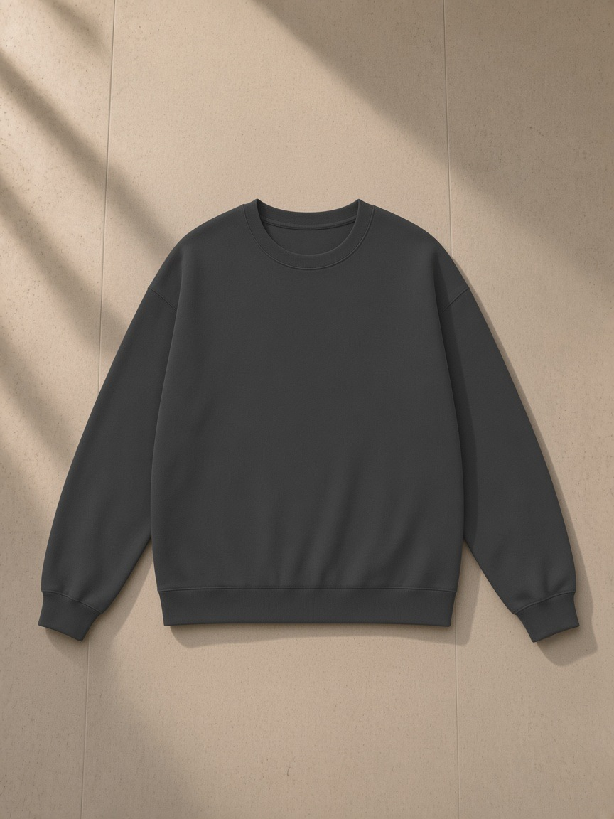 Unisex heavyweight drop shoulder sweatshirt in Charcoal, laid flat on pale limestone