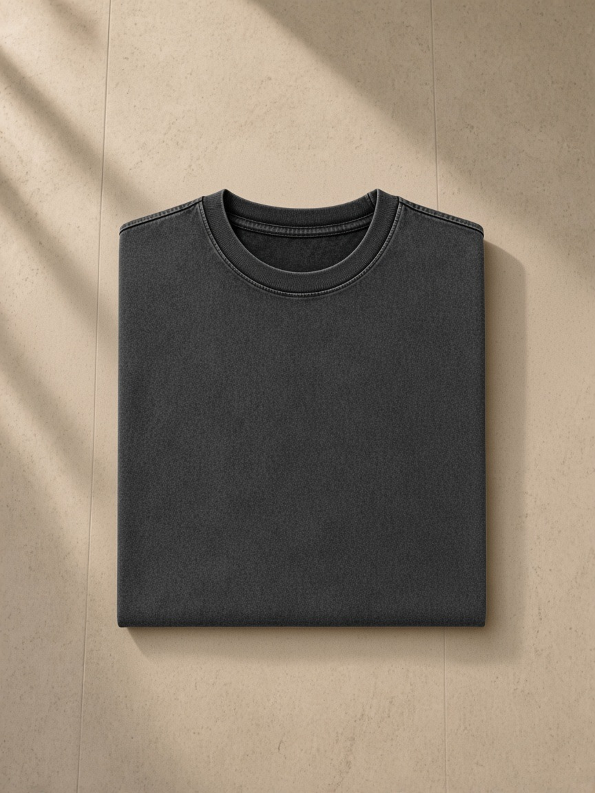 Men's Snow Washed Heavyweight Oversize T-Shirt in Black, folded on pale limestone, detail.