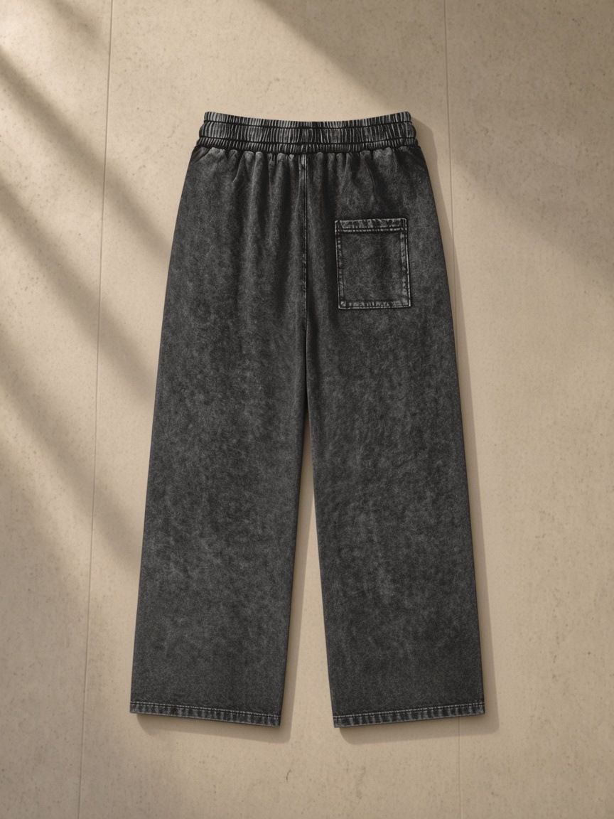 Snow Washed Straight Leg Pants in Black, laid flat on pale limestone, back.