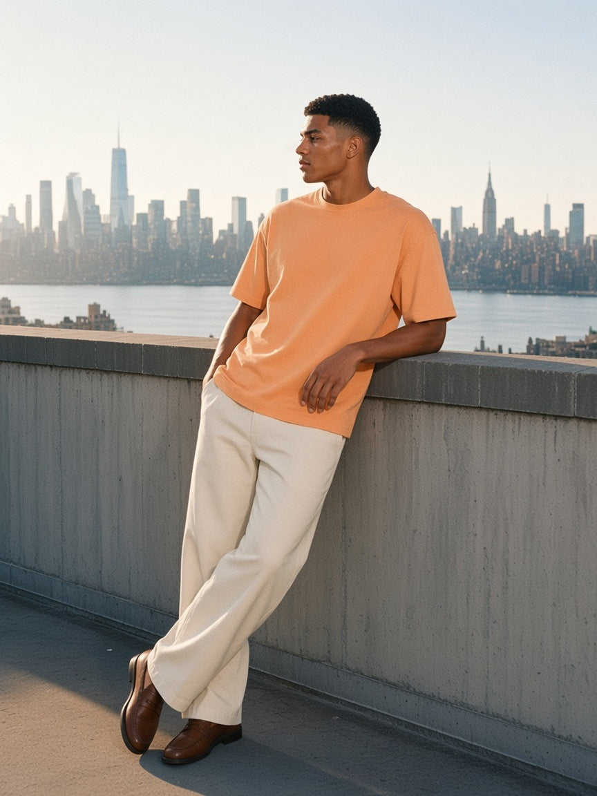 Man in the Classic Loose Boxy Tee in Apricot standing on a rooftop over the Hudson in New York in the morning