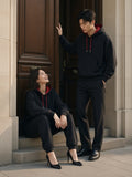Two people in the Contrast Drawstring Hoodie in Black with red lining in a limestone doorway in Paris in the morning