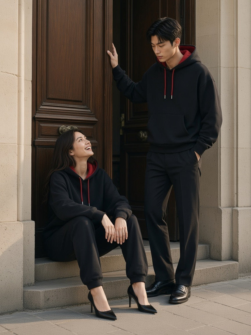 Two people in the Contrast Drawstring Hoodie in Black with red lining in a limestone doorway in Paris in the morning