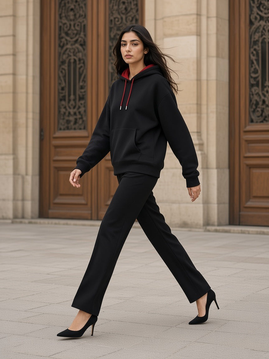 Woman in the Marcel Afters Contrast Drawstring Hoodie in Black with red lining walking through a Paris limestone courtyard