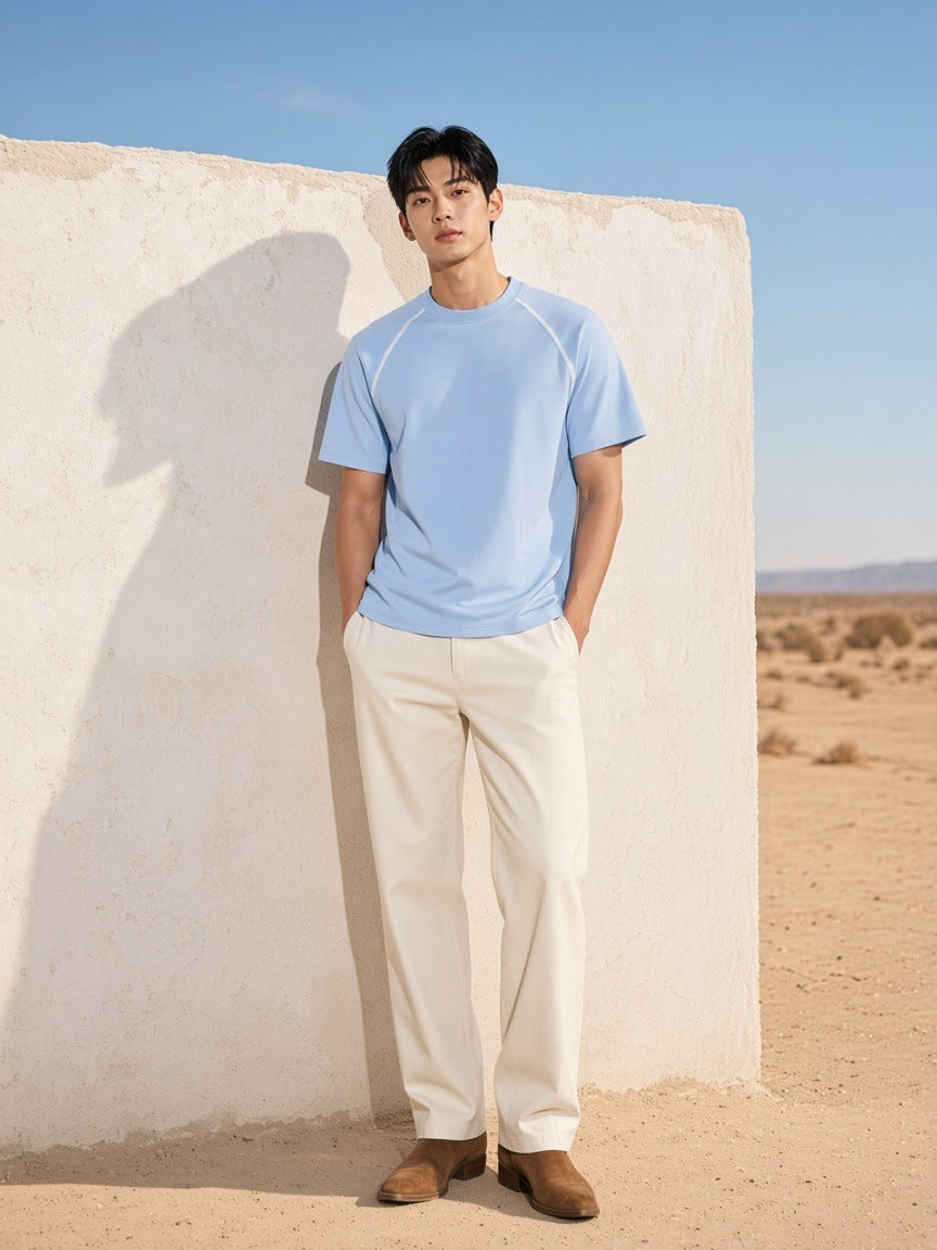 Man in the Contrast Stitch Raglan T-Shirt in Sky Blue against an adobe wall in Marfa, Texas in the morning
