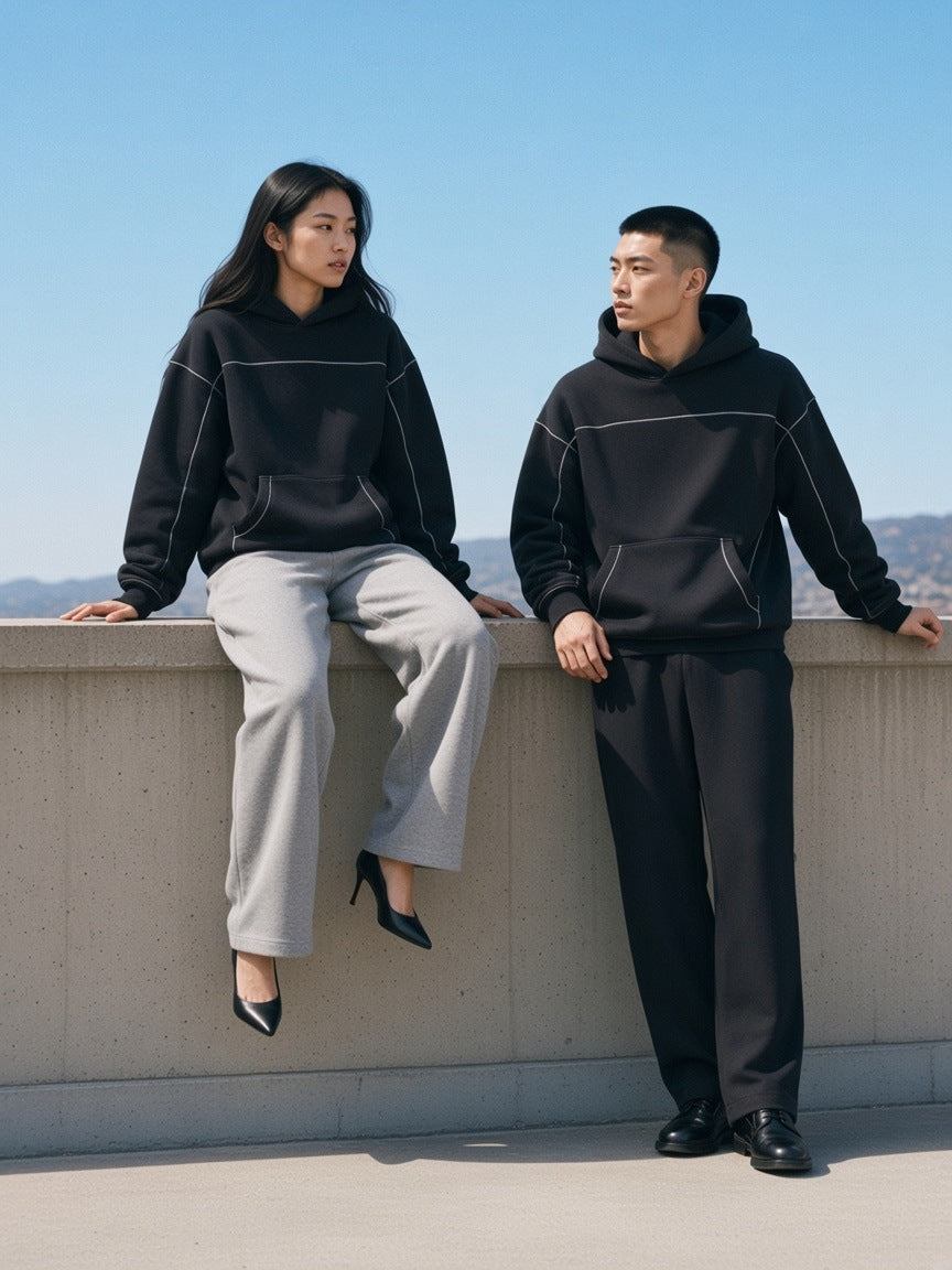Two people in the Contrast-Stitched Boxy Fleece Hoodie in Black striding across a concrete rooftop in LA in the morning