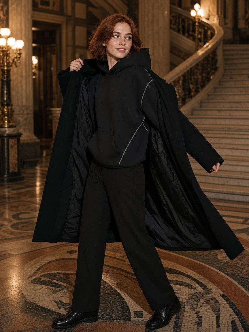 Woman in the Marcel Afters Contrast-Stitched Boxy Fleece Hoodie in Black in a grand hotel lobby in Budapest at night