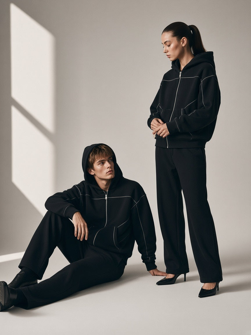 Two people in the Contrast-Stitched Boxy Fleece Zip Hoodie in Black on a warm grey paper studio set in the morning