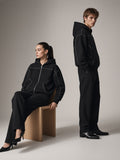 Two people in the Contrast-Stitched Boxy Fleece Zip Hoodie in Black on a warm grey paper studio set